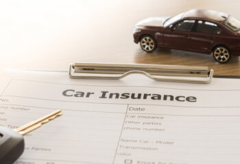 car insurance application form with car model and key remote on desk.
