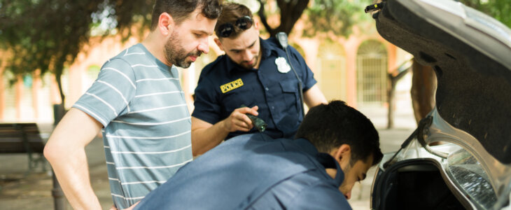 Worried caucasian man waiting for the cops to search his car trunk while searching for a criminal evidence