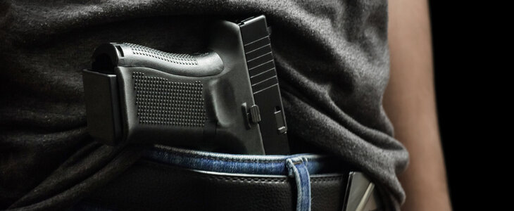 Man drawing a conceal carry pistol from a holster isolated on black background