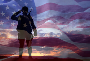 Silhouette of a soldier with USA flag against the sunset