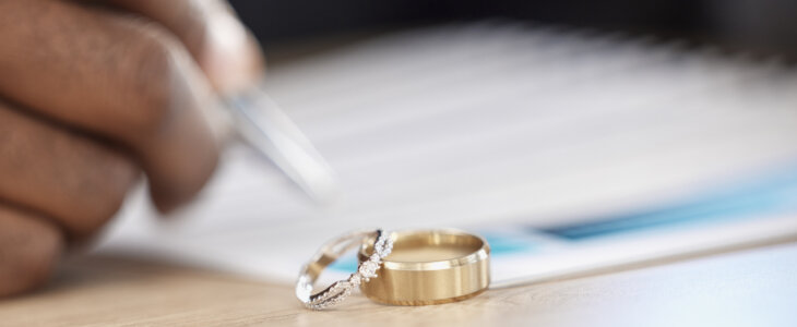 Divorce, rings and signature on paperwork for a lawyer, register wedding or writing on a contract. Table, closeup and a certificate, planning or legal documrnts for a commitment or engagement